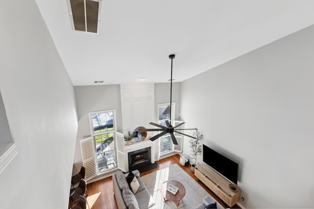 living area featuring wood finished floors, a fireplace with flush hearth, and a ceiling fan