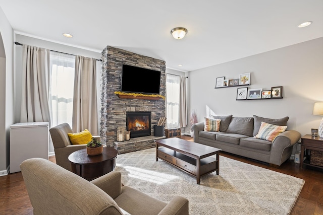 living room featuring recessed lighting, a stone fireplace, and wood finished floors