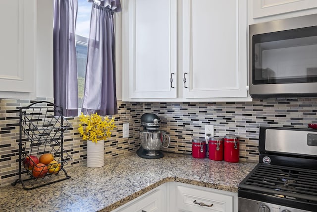 kitchen featuring appliances with stainless steel finishes, white cabinets, and backsplash