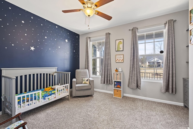 carpeted bedroom featuring wallpapered walls, a crib, multiple windows, and baseboards