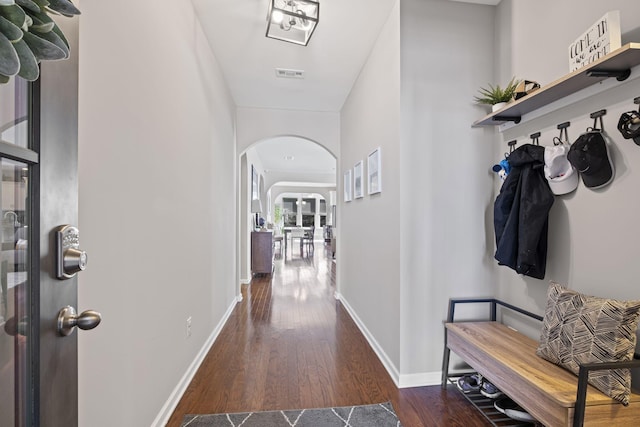 interior space featuring baseboards, visible vents, arched walkways, and wood finished floors