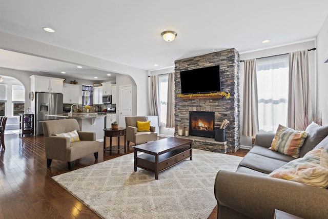 living room with arched walkways, a fireplace, dark wood finished floors, and recessed lighting