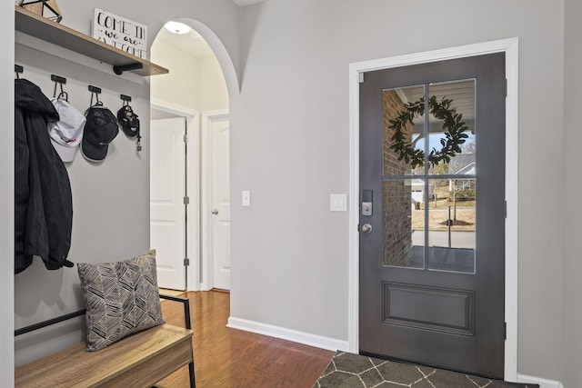 mudroom with arched walkways, baseboards, and wood finished floors