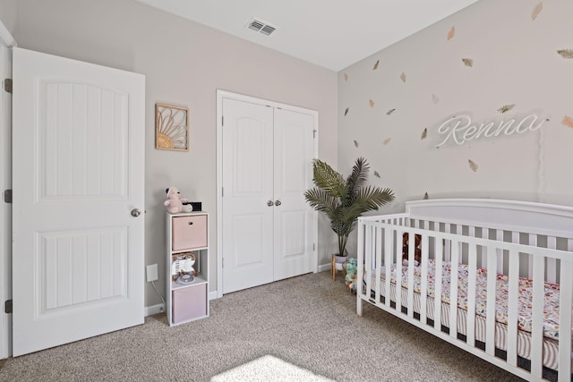 carpeted bedroom featuring a crib, a closet, visible vents, and baseboards