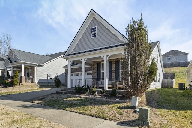 view of front of property featuring driveway, central AC unit, covered porch, a front lawn, and brick siding