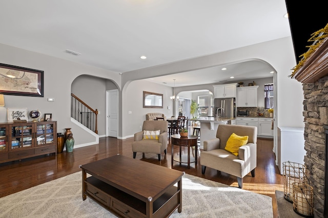 living room featuring visible vents, stairs, arched walkways, and wood finished floors