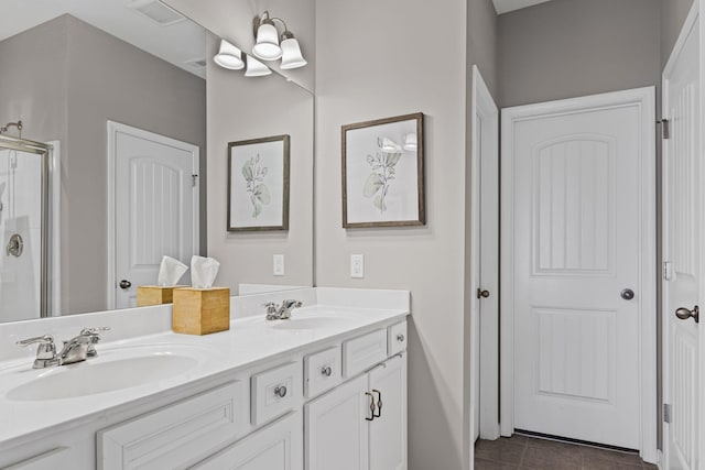 bathroom with a stall shower, double vanity, a sink, and tile patterned floors