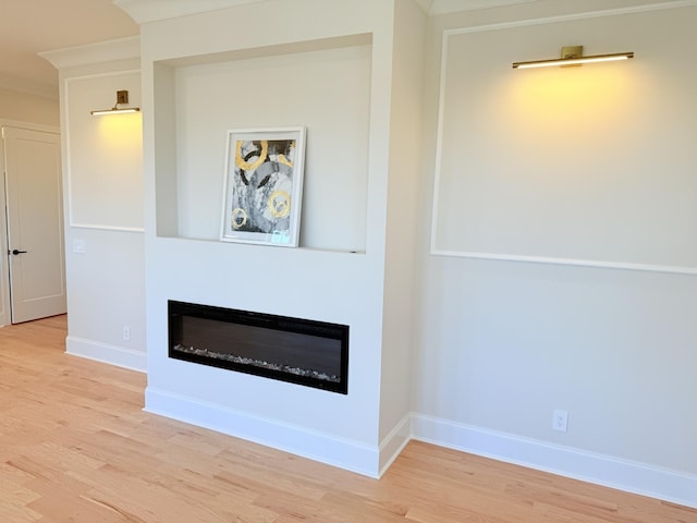 interior details featuring wood finished floors, a glass covered fireplace, and baseboards