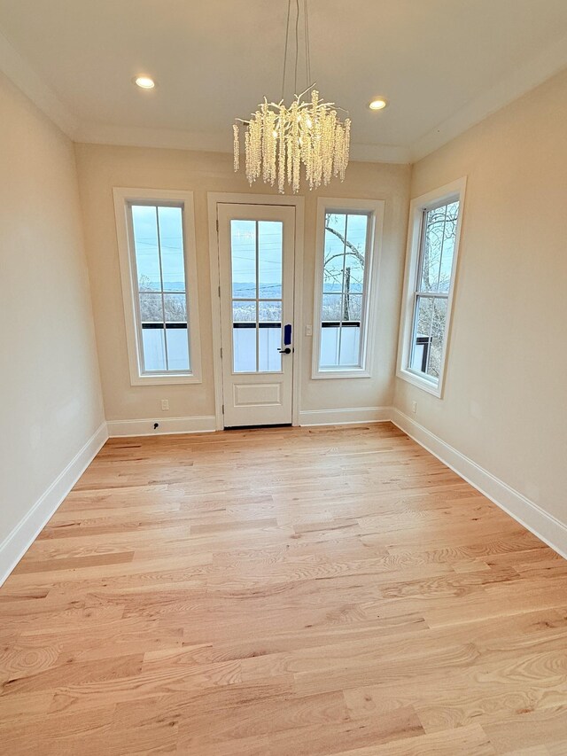 entryway with light wood finished floors, plenty of natural light, an inviting chandelier, and baseboards