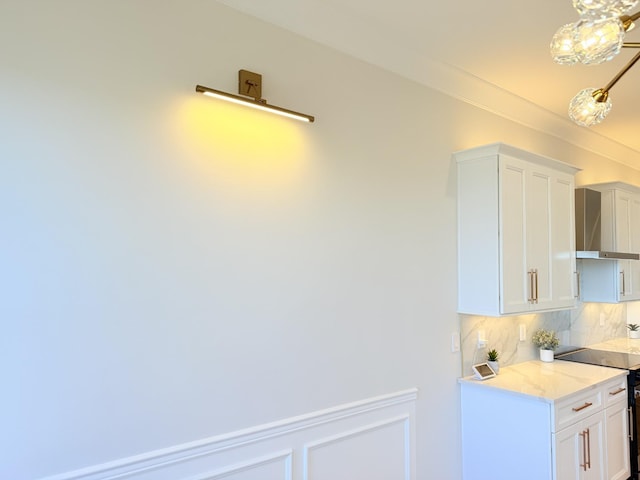 kitchen featuring electric stove, wall chimney exhaust hood, light stone countertops, white cabinetry, and backsplash