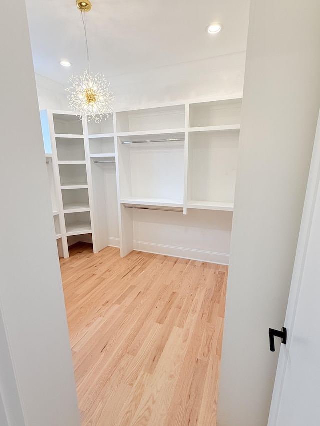 spacious closet with a notable chandelier and wood finished floors