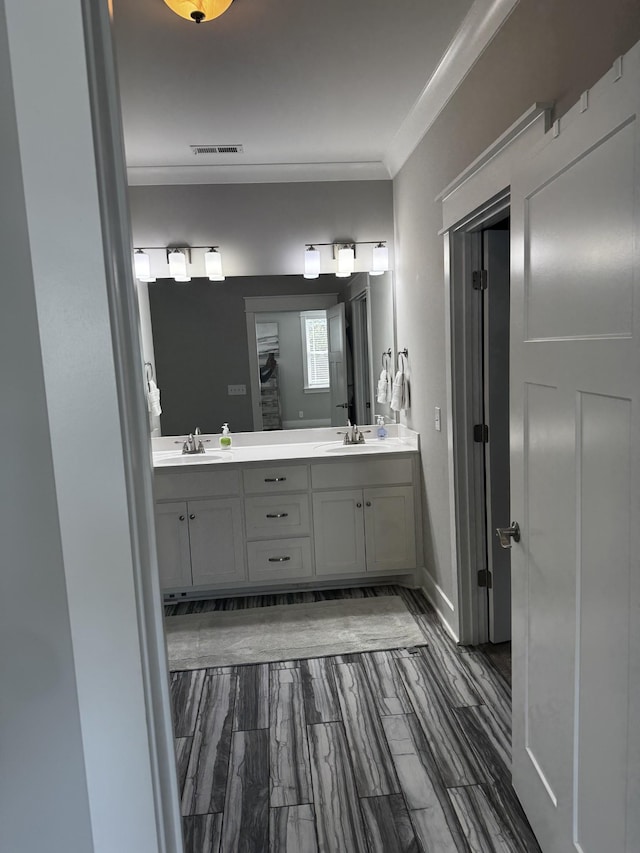 full bathroom featuring double vanity, a sink, visible vents, and crown molding