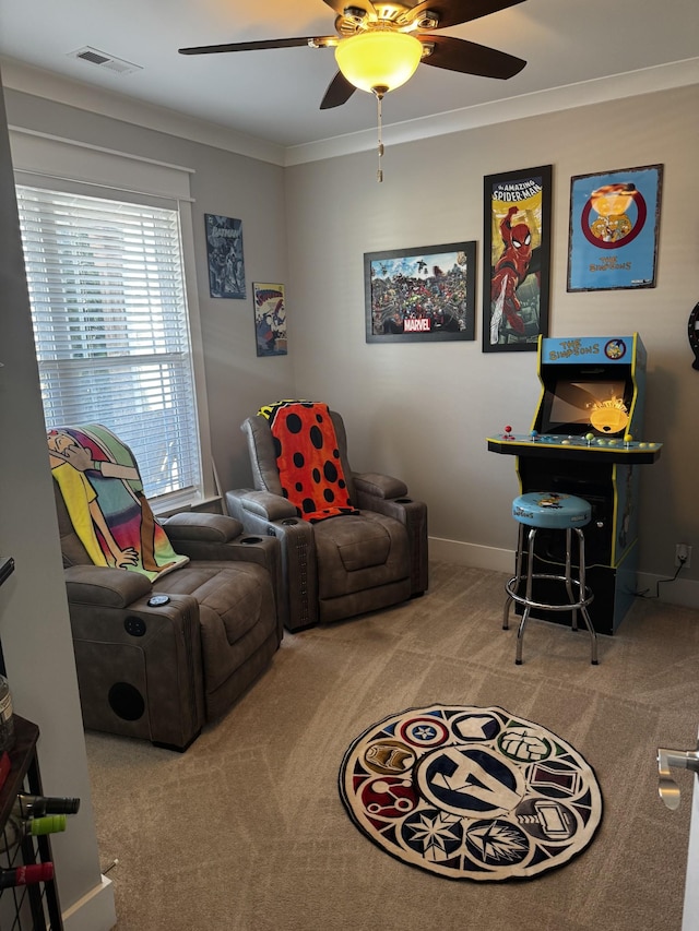 sitting room featuring baseboards, visible vents, a ceiling fan, crown molding, and carpet flooring