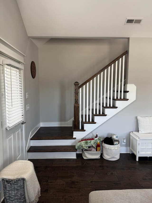 staircase with baseboards, visible vents, and wood finished floors