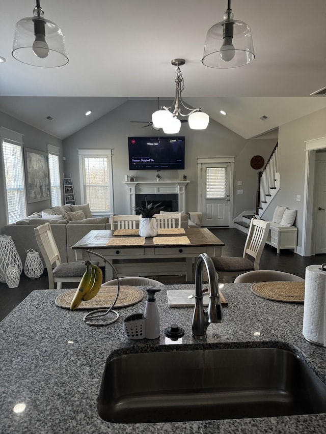 dining space featuring a fireplace, vaulted ceiling, visible vents, and stairs