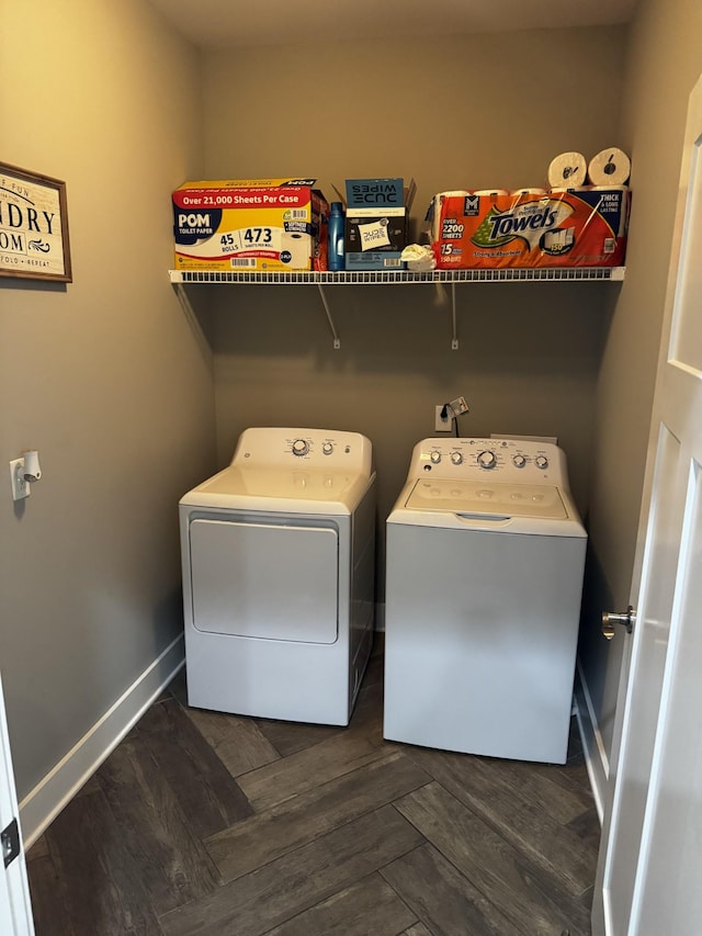 clothes washing area with laundry area, baseboards, dark wood finished floors, and washing machine and clothes dryer