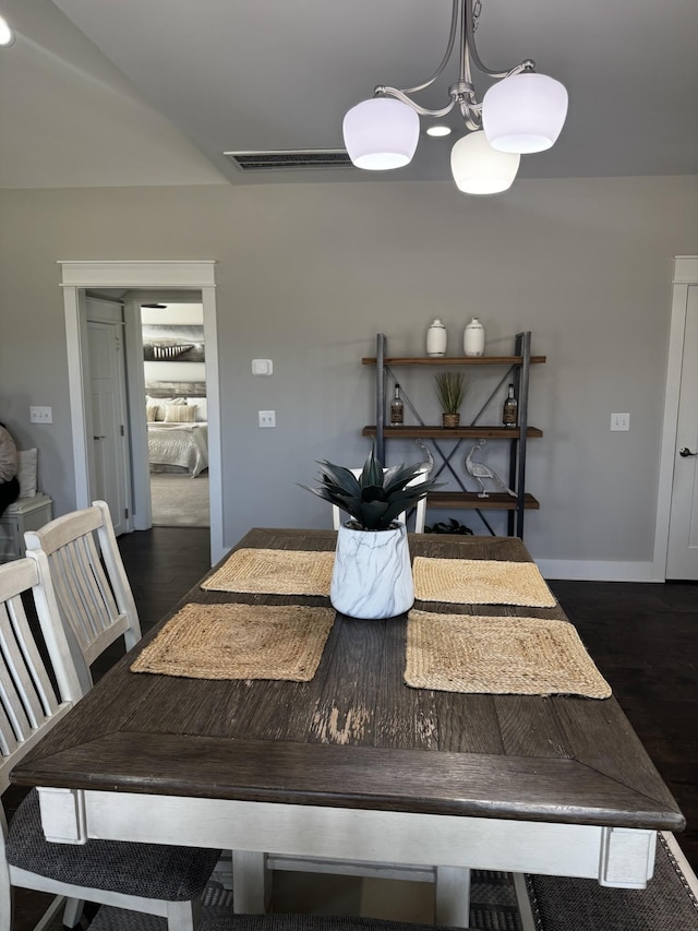 dining room with a notable chandelier, dark wood-type flooring, and baseboards