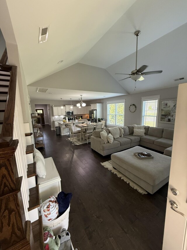 living area featuring visible vents, ceiling fan with notable chandelier, vaulted ceiling, and dark wood finished floors