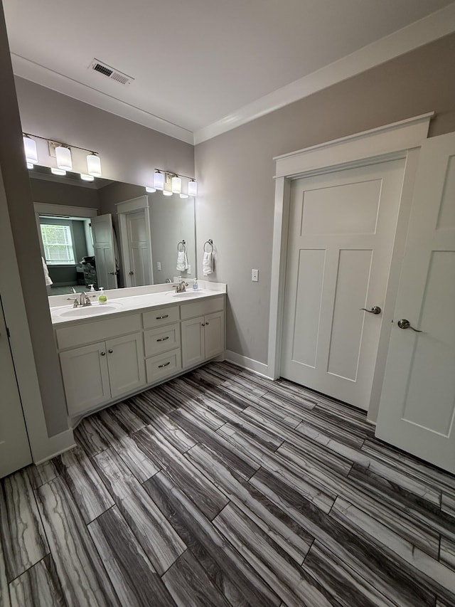 bathroom featuring a sink, double vanity, visible vents, and wood finished floors