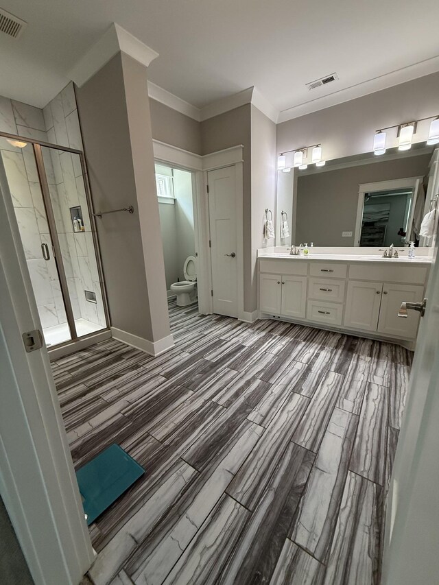 full bathroom featuring a stall shower, double vanity, visible vents, and wood finished floors