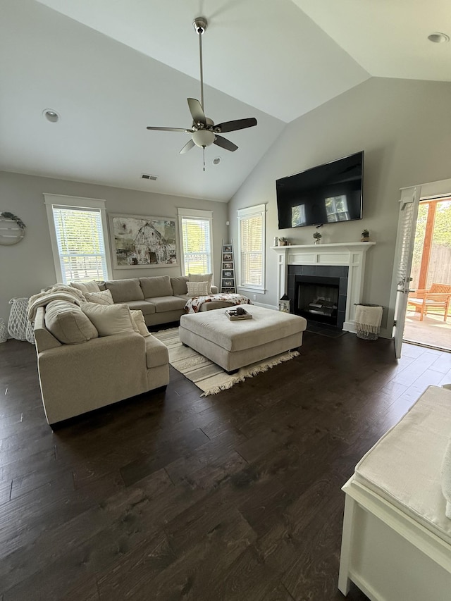 living room with a tile fireplace, ceiling fan, vaulted ceiling, and a healthy amount of sunlight