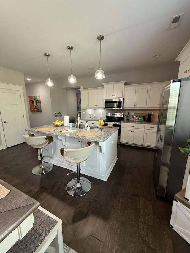 kitchen featuring stainless steel appliances, dark wood-type flooring, visible vents, light stone counters, and white cabinets