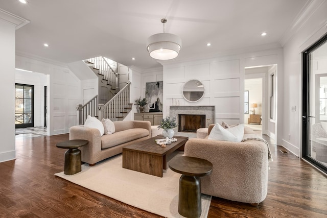 living area featuring ornamental molding, a fireplace, dark wood finished floors, and a decorative wall