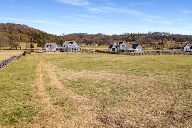 view of yard with a rural view, fence, and a view of trees