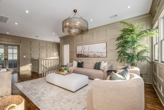 living area with visible vents, a decorative wall, and a chandelier