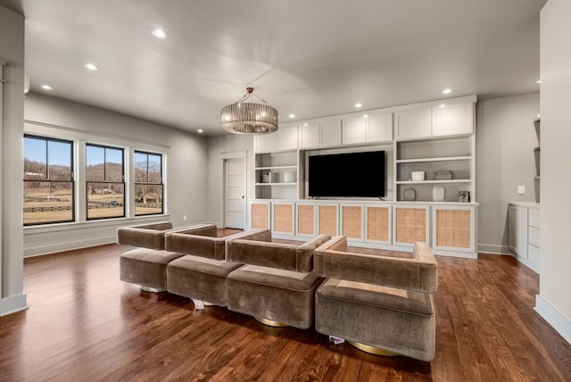 living room featuring built in shelves, dark wood finished floors, recessed lighting, an inviting chandelier, and baseboards