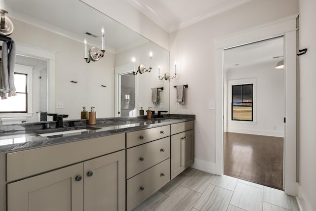 bathroom with double vanity, crown molding, visible vents, and a sink