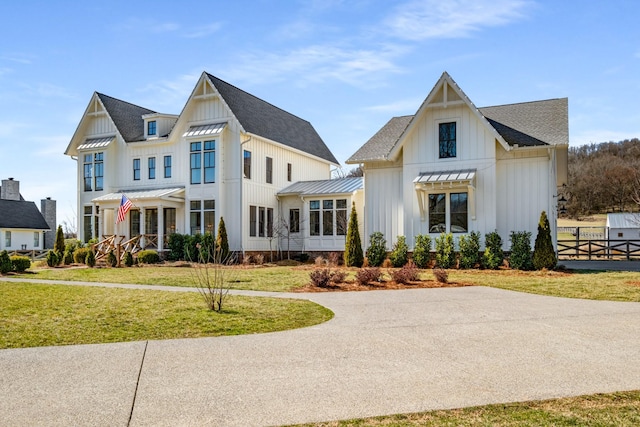 modern farmhouse with a shingled roof, board and batten siding, a front yard, a standing seam roof, and metal roof