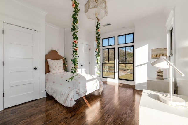 bedroom with visible vents, crown molding, and wood finished floors