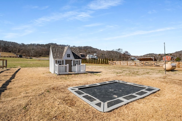 view of yard featuring an outbuilding, a rural view, and fence