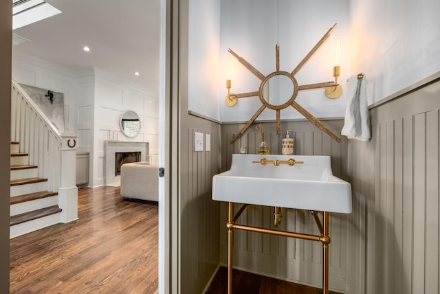 bathroom with a large fireplace, a decorative wall, wood finished floors, and recessed lighting