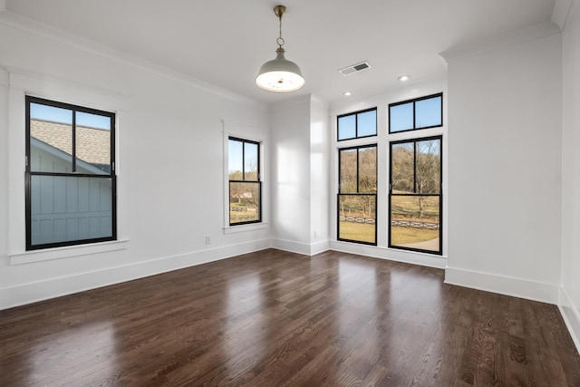 empty room featuring plenty of natural light, baseboards, visible vents, and crown molding