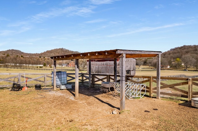 view of yard with a mountain view, an outbuilding, and a rural view