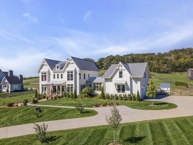 view of front of property with a standing seam roof, driveway, a front lawn, and board and batten siding