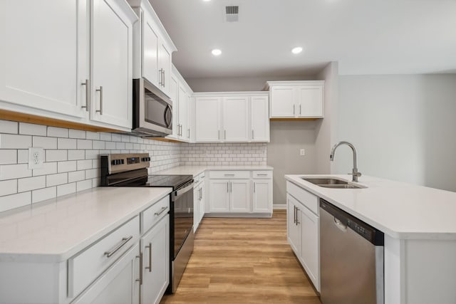 kitchen featuring a sink, visible vents, white cabinetry, appliances with stainless steel finishes, and light wood-type flooring