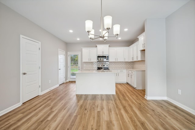 kitchen featuring light wood finished floors, stainless steel appliances, light countertops, decorative backsplash, and baseboards