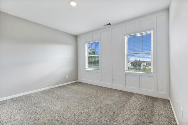 empty room featuring baseboards, carpet floors, visible vents, and a healthy amount of sunlight