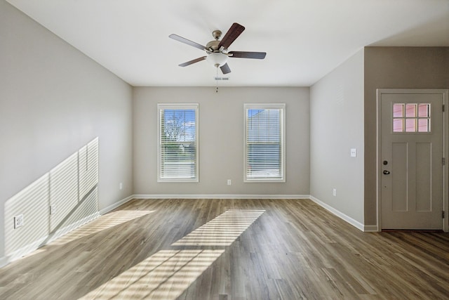 unfurnished living room featuring a ceiling fan, baseboards, and wood finished floors