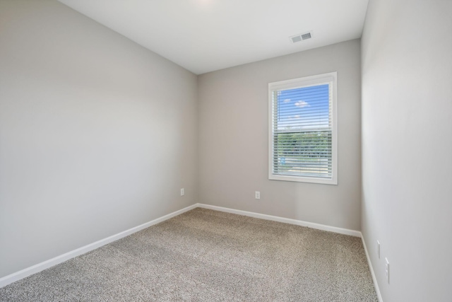 empty room with carpet, visible vents, and baseboards