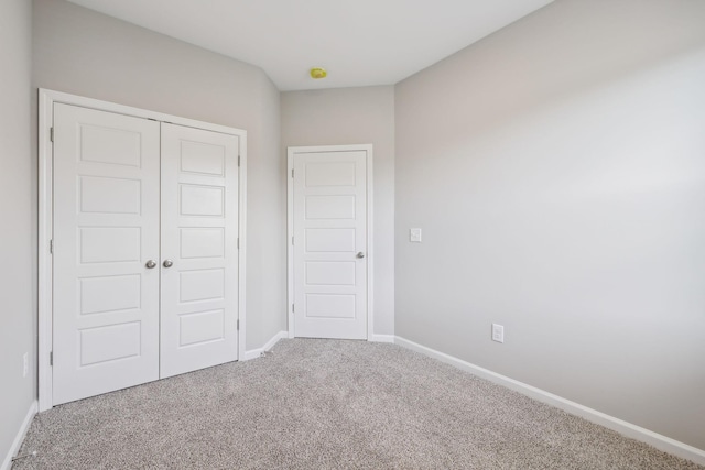 unfurnished bedroom with a closet, baseboards, and carpet flooring