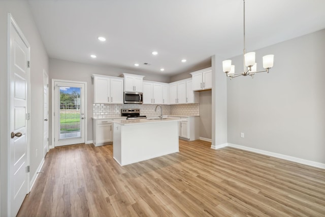 kitchen with tasteful backsplash, appliances with stainless steel finishes, light wood-style flooring, and a sink