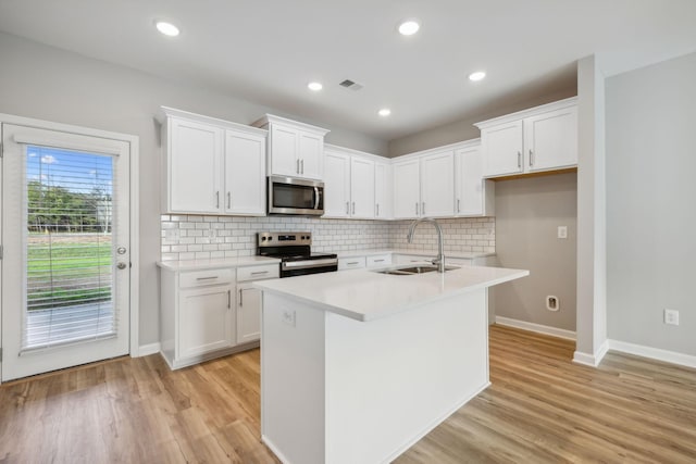 kitchen with light countertops, appliances with stainless steel finishes, a sink, and light wood-style flooring