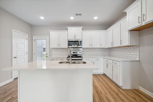 kitchen with stainless steel appliances, light wood-style flooring, visible vents, and decorative backsplash