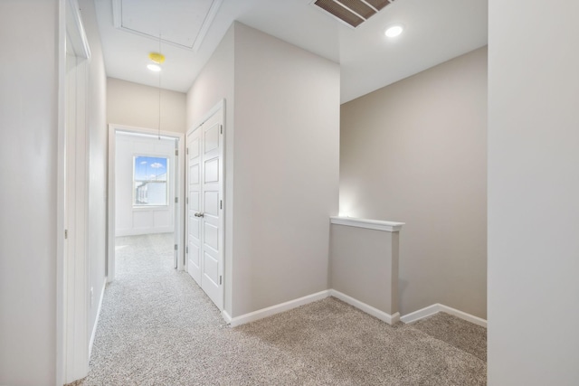 hall with attic access, visible vents, carpet floors, and baseboards