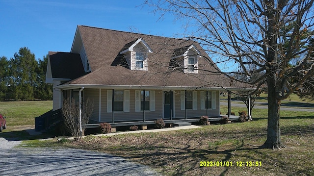 view of front of home with a shingled roof, a front yard, and covered porch