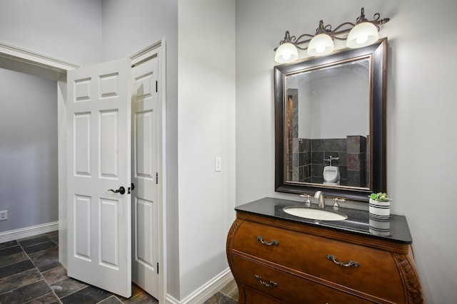 bathroom with stone finish floor, vanity, and baseboards